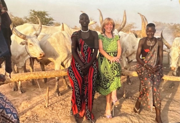 Grabbing life by the horns in South Sudan: Franci Neely standing beside Mundari people at the Mundari cattle camp outside Juba, South Sudan, on Feb. 19, 2022