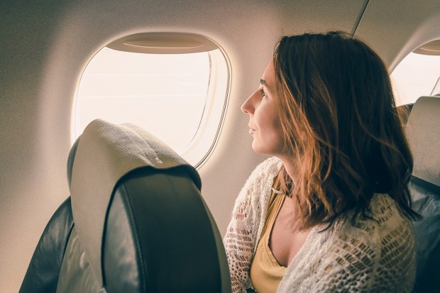 Traveler girl watching through airplane window